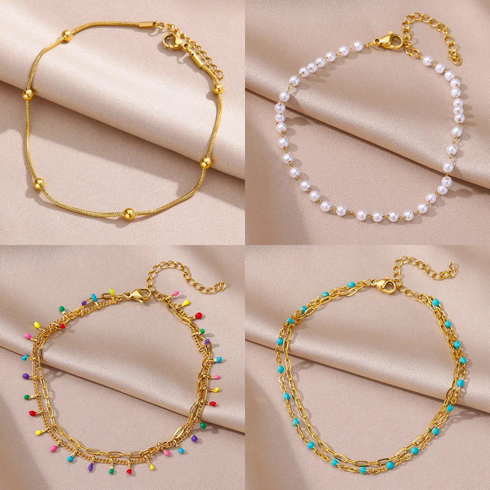 Gold-tone chain anklet with small pearl detailing, worn above bare foot.