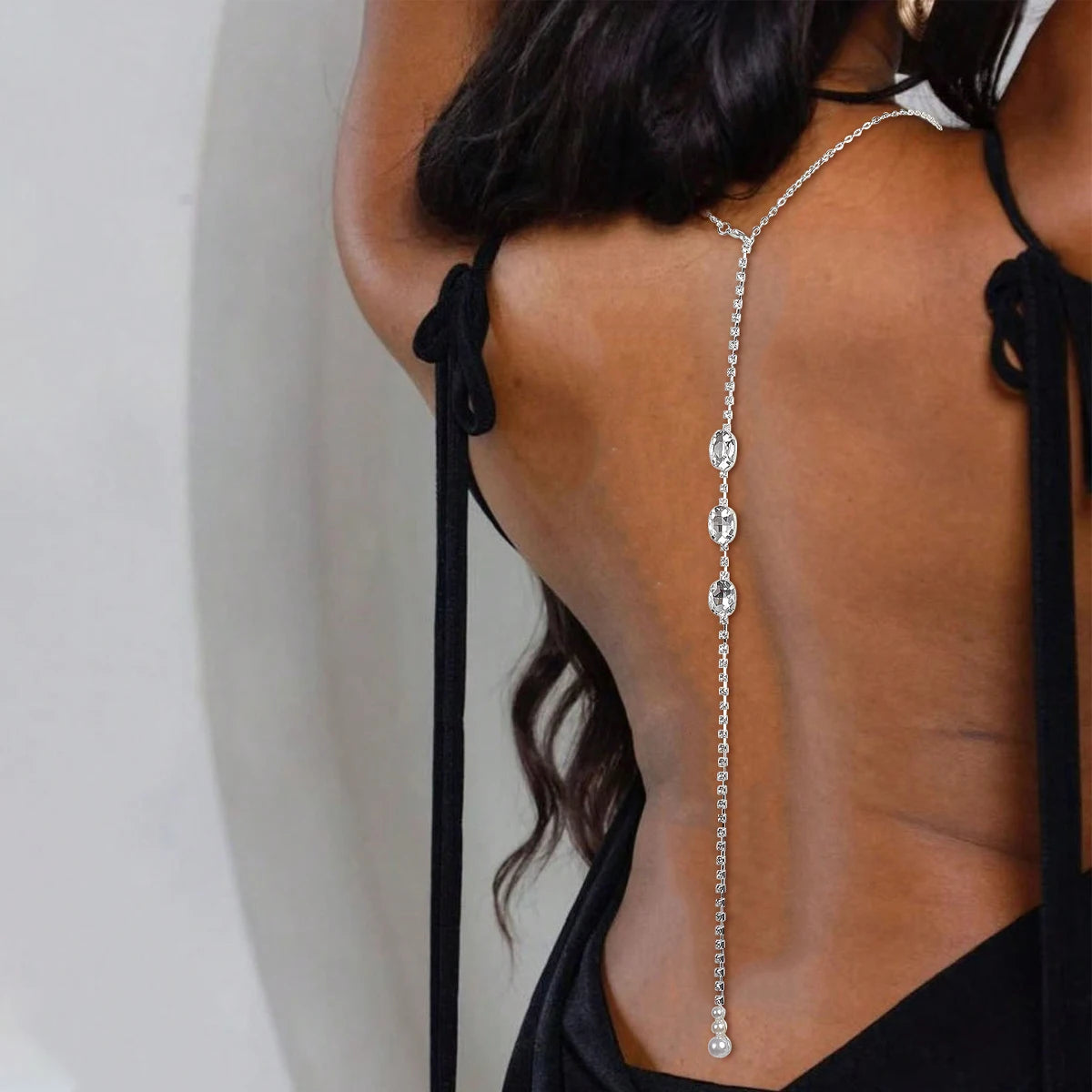 Rhinestone back chain with hanging waterdrop stones, worn with an open-back dress.